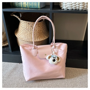 Pink nylon tote bag detail with leather flap and cute plush dog pendant on white carpet