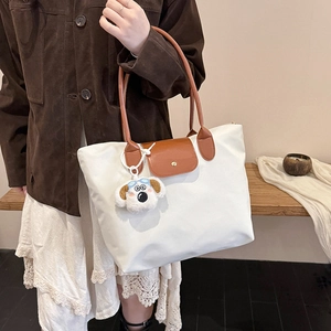 Large white nylon tote bag with brown leather handles and plush dog charm for women
