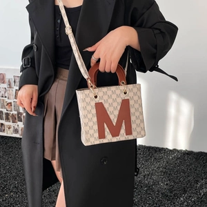 Retro canvas tote bag with M-print and leather handles shown on a model in a studio set