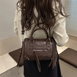 Brown faux leather Boston bag with silver studs and tassel detail shown on model