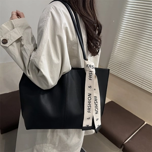 Minimalist black tote bag with vertical stitching and decorative white fashion ribbon
