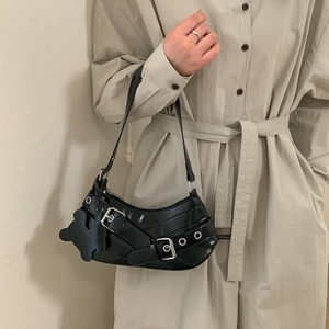 Detail of black faux leather crescent bag with silver buckle and bear charm on model