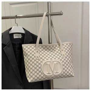 Detail of cream tote bag featuring M-letter monogram print and textured 3D logo detail