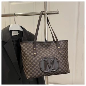 Detail of a dark brown tote bag with M letter monogram print hanging on a metal rack