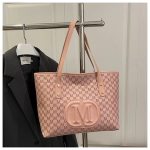 Close-up of light pink tote bag featuring embossed M logo and monogram floral print