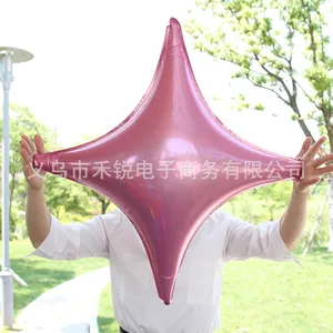 Pink metallic four-pointed star foil balloon held in hand for outdoor party decoration