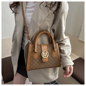 Close-up of retro brown crossbody bag with letter M monogram pattern and gold logo buckle
