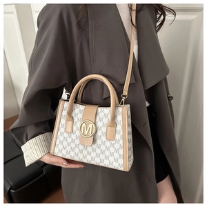 Close-up of printed letter patterns and gold metal logo on the ladies handbag