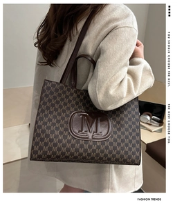 Detail of vintage brown tote bag with M-pattern print and embossed central logo