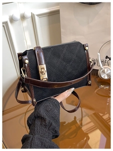 Détail du sac à main en daim noir matelassé avec fermoir doré et bandoulière brune