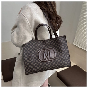 Detail of vintage brown tote bag with M-pattern monogram and embossed leather logo