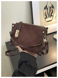 Vue détaillée du sac bandoulière marron matelassé avec fermoir doré tournant