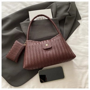 Detail of woven brown tote bag texture and matching small zipper pouch on a grey suit