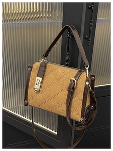 Détail du sac en toile matelassée avec finitions en cuir marron et fermoir doré rotatif
