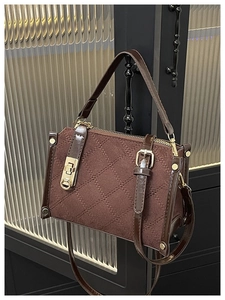 Détail du sac bandoulière matelassé marron foncé avec finitions dorées et cuir suédé