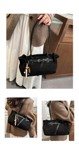 Detail of black suede tote bag featuring ethnic beaded tassel and vintage metal buckle strap