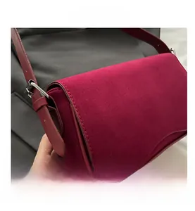 Detail of burgundy suede shoulder bag showing silver metal buckle and premium texture