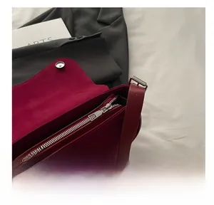 Detail view of wine red matte underarm bag featuring silver zipper and inner pocket