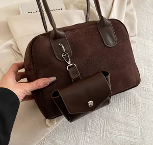 Détail d'un sac à main en daim marron foncé avec mini breloque en cuir et boucle argentée
