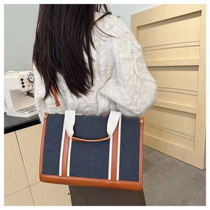 Detail van de blauwe denim tas met bruine lederen bies en witte handvaten