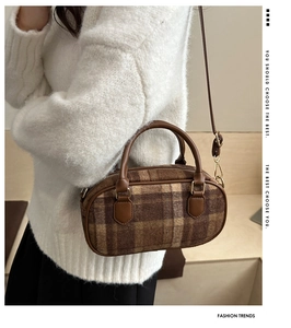 Detailed view of brown plaid bowling bag showing textured wool fabric and leather strap