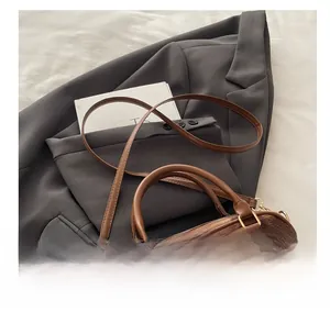 Close-up of brown plaid plush handbag featuring durable leather straps and metal hardware