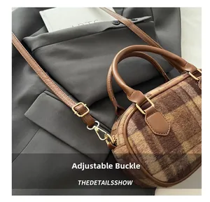 Close-up of adjustable metal buckle on a brown plaid wool crossbody bag for winter