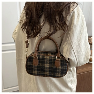 Close-up of vintage plaid pattern and brown leather handle on wool shoulder bag
