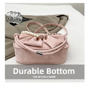 Détail du sac à main rose texturé avec poignée en perles et base résistante