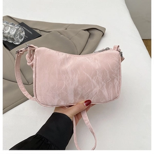 Détail du sac à bandoulière rose clair avec texture plissée et design de bandoulière nouée
