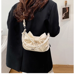 Détail du sac bandoulière blanc cassé avec nœud plissé et chaîne de perles décorative
