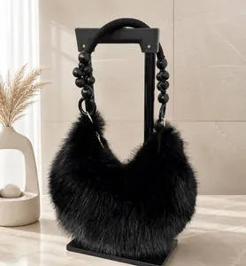 Détail d'un sac à main en peluche noire avec poignée perlée et texture douce d'hiver