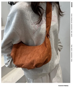 Detail of caramel brown suede hobo bag with knot strap on shoulder of a model
