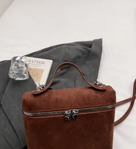Detail of a brown matte texture bag featuring distinctive double heart-shaped silver zippers