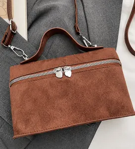 Detail of brown suede handbag with heart zippers on a grey suit background