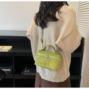 Macro shot of green suede crossbody box bag showing refined texture and silver zipper detail