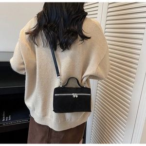 Detail of matte black handbag featuring a unique heart-shaped silver metal zipper puller