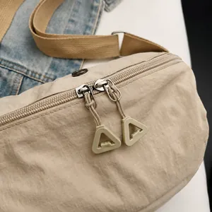 Detalle de bolso de nylon beige con cremalleras dobles y correa marrón claro