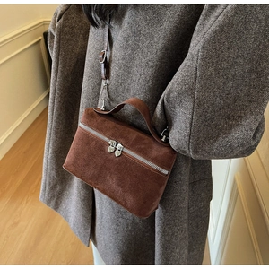 Détail d'un sac à main en daim marron avec deux fermetures éclair en métal en forme de cœur