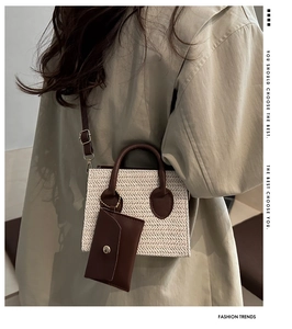 Detail of straw woven crossbody bag with brown leather strap and small pouch pendant