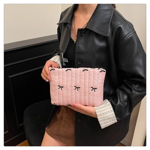 Dettaglio di una pochette trapuntata rosa con fiocchi neri ricamati e texture morbida