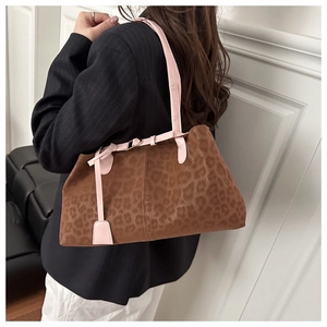Detail of leopard print tote bag with pink straps worn by a model in a blazer