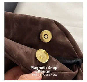 Gros plan sur le fermoir magnétique doré d'un sac à main en cuir marron grainé
