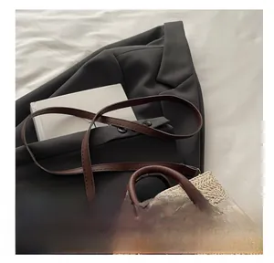 Detailed macro view of woven straw handbag with adjustable brown leather shoulder strap