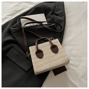 Detail of herringbone weave texture and brown leather strap on cream crossbody bag
