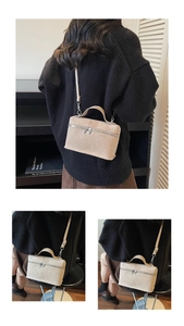Detail view of the beige frosted box bag showing top handle and silver double zipper