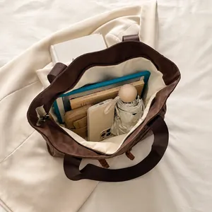Vue de dessus montrant la grande capacité du cabas marron avec livres, iPad et parapluie