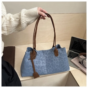 Détail du cabas bleu à motif léopard avec anses en cuir marron et coutures blanches