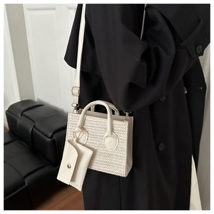 Detail view of cream woven crossbody bag featuring a matching detachable coin purse