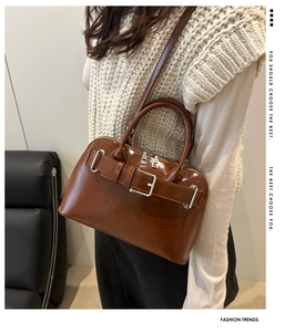 Detail of a brown patent leather crossbody bag with silver buckle and shoulder strap